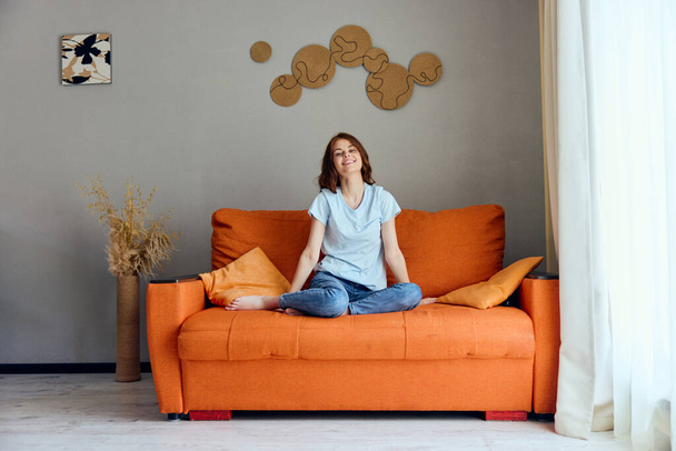 portré egy nőről a narancssárga kanapén a pihenőszobában pózoló lakások - Fotó, kép