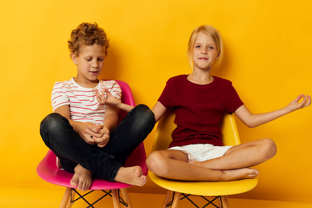 Small children childhood sitting on chairs together on colored background - Foto, Bild