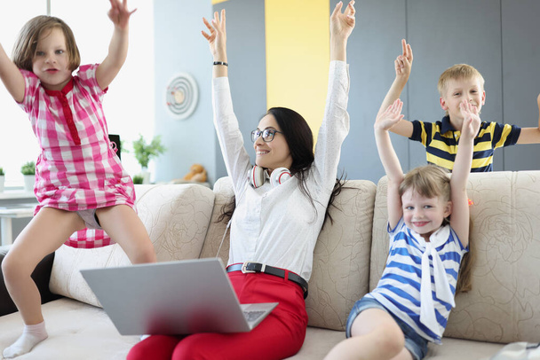 Woman with laptop and children rejoicing and raising their hands up at home - Photo, image
