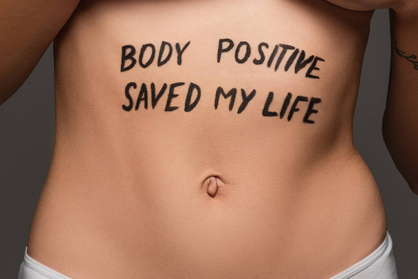 cropped view of young woman with body positive saved my life lettering on belly isolated on grey - Photo, Image