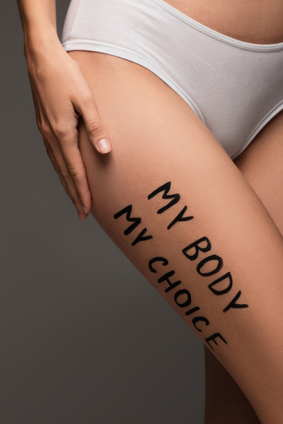 vista parcial de la mujer en bragas, con mi cuerpo mi elección letras en la cadera aislado en gris oscuro - Foto, Imagen