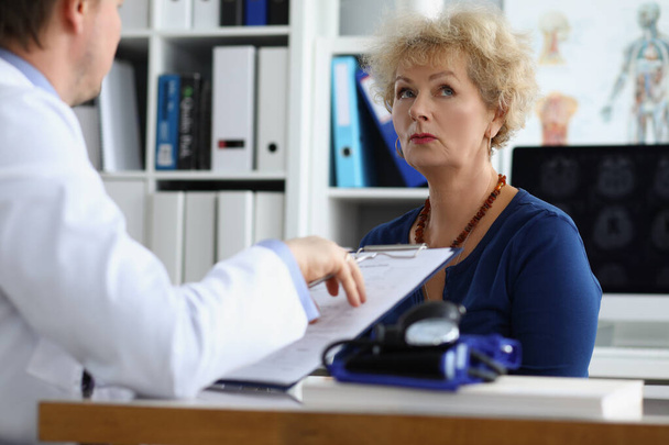 Lääkäri haastattelemalla iäkäs nainen potilas klinikan toimistossa - Valokuva, kuva