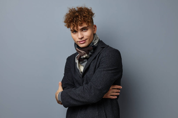 Attractive man in a coat a checkered scarf Gray background - Foto, immagini
