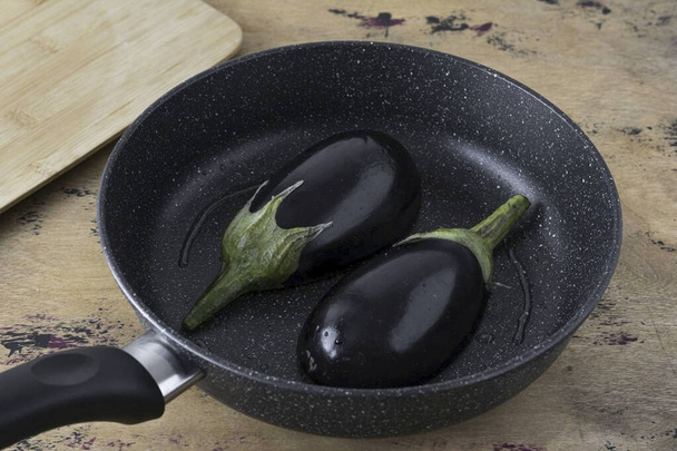 Heat up a frying pan with a little oil. Lay the eggplant cut side down. Fry for a few minutes until the skin is slightly browned. - Photo, Image