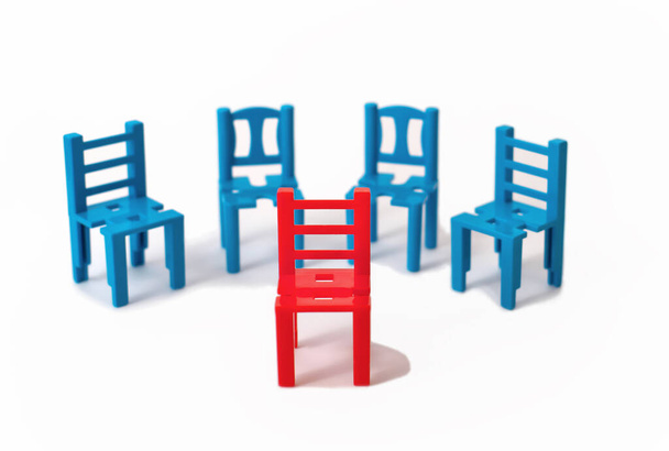 片方の赤い椅子がもう片方の青の外に立っています。個性的で個性的なコンセプトになっています。群集から目を離さず. - 写真・画像