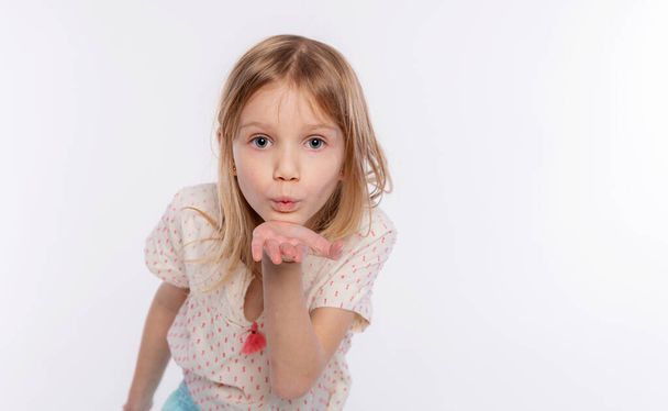 Caucasian kid girl looking at the camera blowing a kiss with hand on air being lovely. Love expression on white background - Photo, Image