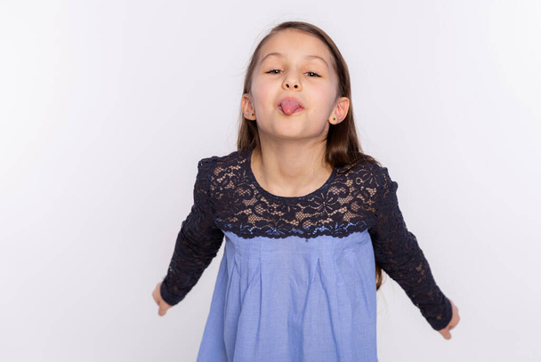 Kid funny girl fooling around teases and shows tongue isolated on white background. Face expression - Photo, Image