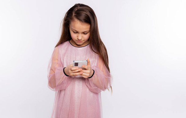 Кавказька дівчинка дивиться на екран відео чи текст на мобільному телефоні, ізольований над білим фоном вільне місце для тексту - Фото, зображення