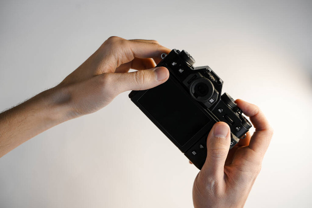 een man houdt een compacte moderne SLR camera op zijn hand op een witte achtergrond bovenaanzicht - Foto, afbeelding
