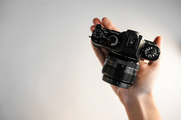 un uomo tiene una fotocamera reflex moderna compatta sulla mano su uno sfondo bianco vista dall'alto - Foto, immagini