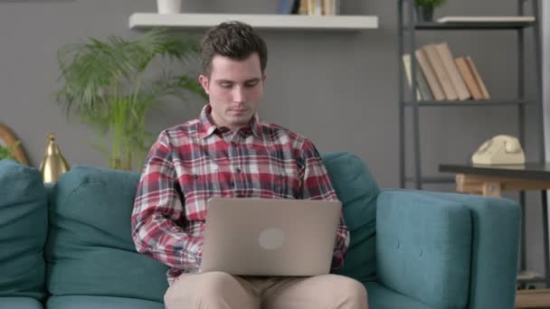 ソファの上に親指を示すラップトップを持つ男  - 映像、動画