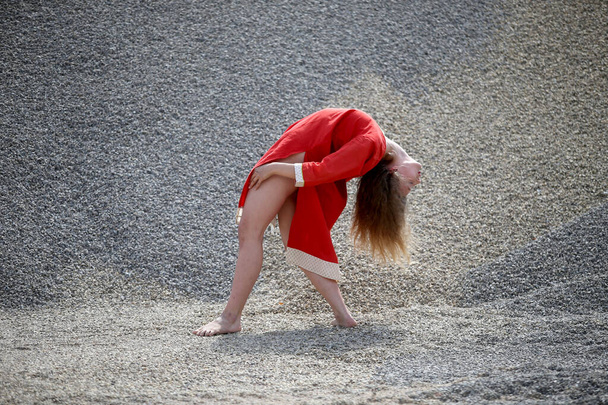 Krásné červené šaty s kudrnaté vlasy tance na pozadí písečné duny. - Fotografie, Obrázek
