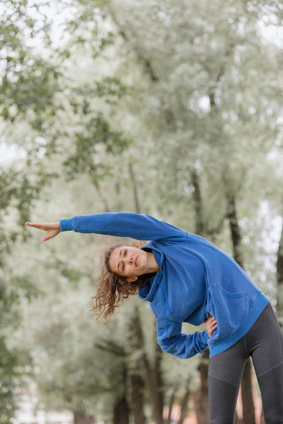a European woman does sports in a park or a public place. warm-up and jogging in the fresh air - Foto, immagini