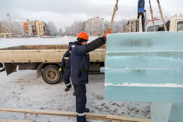 Slinger συναρμολογητής σε ένα μπλε σακάκι εκφόρτωση πάνελ πάγου χρησιμοποιώντας γερανό φορτηγό - Φωτογραφία, εικόνα