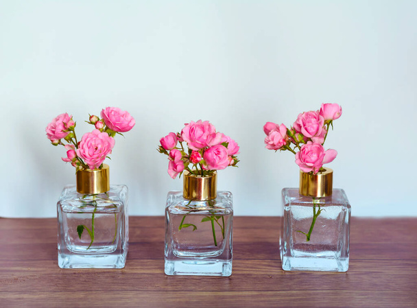 Krásné růžové růže ve skleněných vázách na dřevěném pozadí.Home dekorační prvky - Fotografie, Obrázek