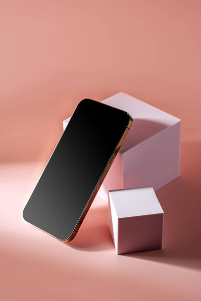 Smartphone with blank black screen. Mobile phone on cube podium.  Pedestal mockup space for display of app.    - Фото, зображення