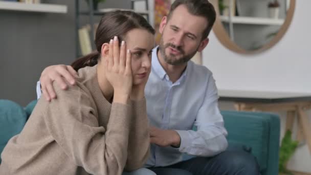 Hombre tratando de reconfortar a su pareja femenina en el sofá  - Metraje, vídeo