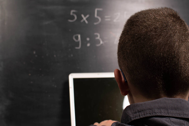 Child with laptop calculates in front of the blackboard - Photo, Image