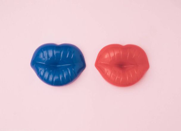 Kék és piros ajkak egymás mellett, világos rózsaszín háttérrel. A minimális koncepció egy szerelmes párról - Fotó, kép