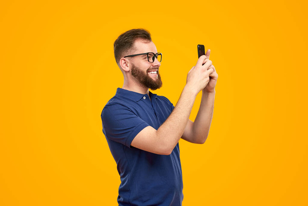 Cheerful man taking photo via smartphone - Foto, Imagen