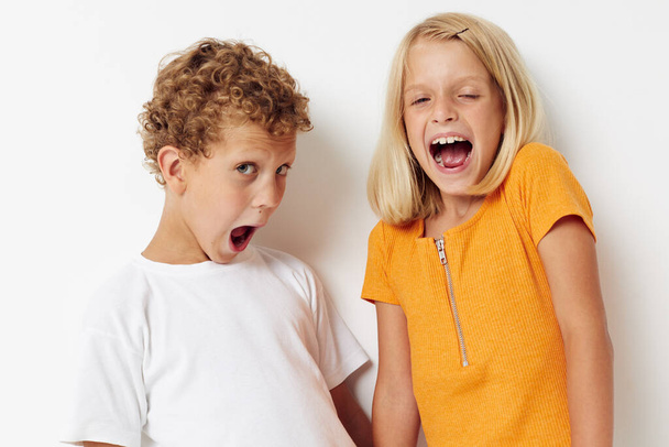 due bambini gioiosi vestiti casual posa emozioni studio isolato sfondo inalterato - Foto, immagini