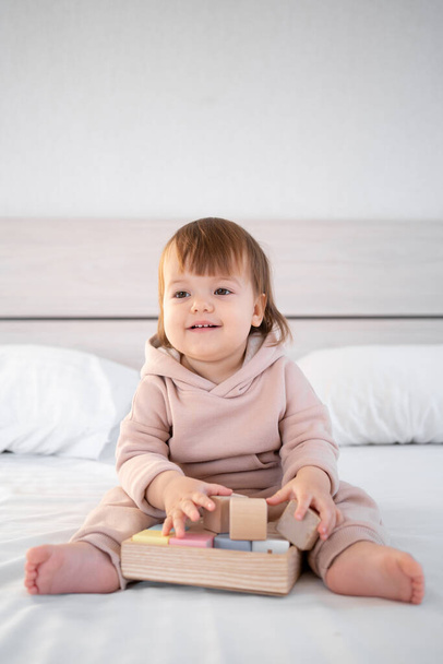 klein schattig kind spelen met speelgoed kubussen zitten op bed thuis. kopieerruimte. - Foto, afbeelding