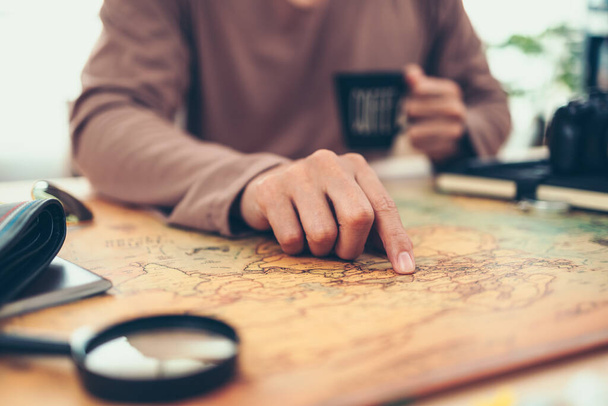 Tourist planning vacation, holiday with the help world map. Man's hand marks route on map and using pins and rope. Travel concept. - 写真・画像