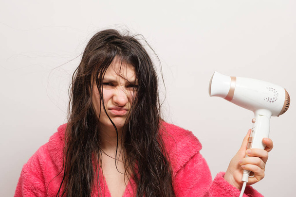 Ruskeahiuksinen nainen kuivattaa sen hiustenkuivaajalla. Hiustenhoito, ylikuivat hiukset - Valokuva, kuva
