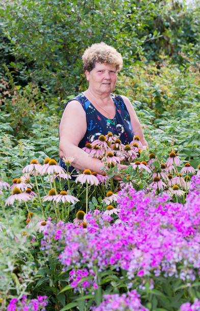 mature woman with flowers at garden - Фото, изображение