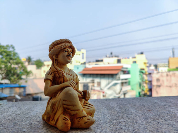 Foto de stock de hermosa escultura hecha a mano de madera o estatua del hombre Rajasthani, con turbante y paños tradicionales sentados en el piso.Imagen capturada bajo luz natural en Bangalore, Karnataka. - Foto, imagen