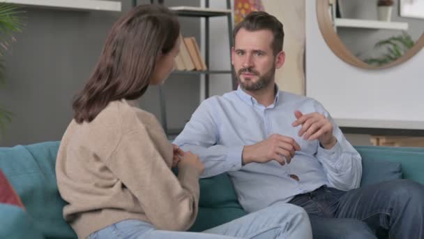 Σοβαρός άντρας που μιλάει με γυναίκα ενώ κάθεται στον καναπέ  - Πλάνα, βίντεο