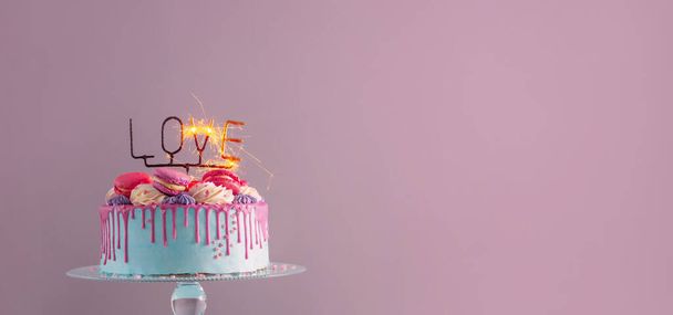 cake with pink and blue decor and burning sparkler with text love - Фото, изображение