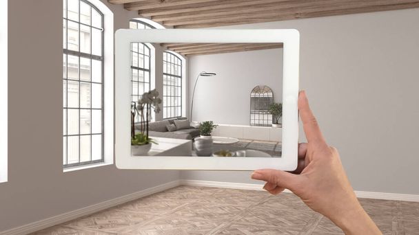 Augmented reality concept. Hand holding tablet with AR application used to simulate furniture and design products in empty interior with parquet floor, living dining room and kitchen - Photo, Image