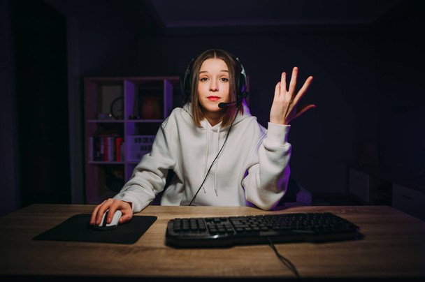 Озадаченная женщина-геймер бросается играть онлайн с наушниками на голове и микрофоном, глядя на камеру с удивленным лицом. Концепция игры - Фото, изображение