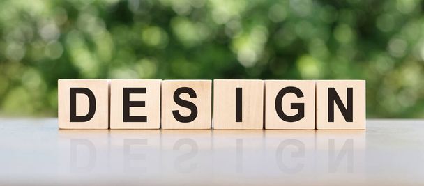 DESIGN word written on wooden blocks. The text is written in black letters and is reflected in the mirror surface of the table. Business concept for your design. - Fotoğraf, Görsel