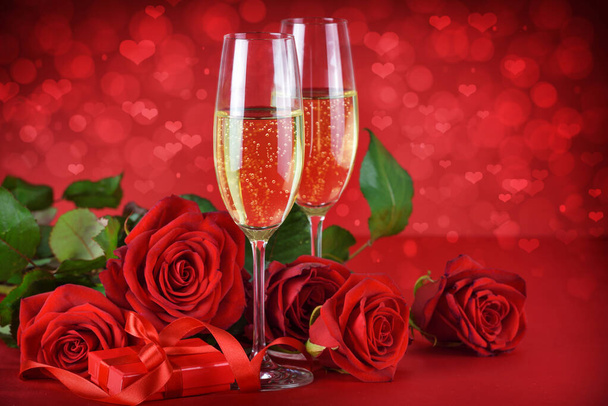 Concept romantique de soirée de rendez-vous. Champagne, cadeau et roses sur fond rouge festif avec des cœurs. - Photo, image