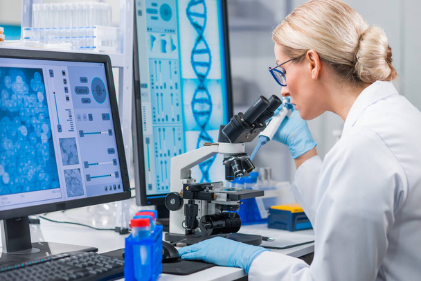 Professional female scientist is working on a vaccine in a modern scientific research laboratory. Genetic engineer workplace. Future technology and science. - Photo, Image