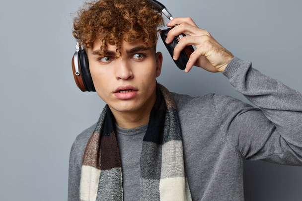 handsome young man plaid scarf wireless headphones technology light background - Foto, afbeelding