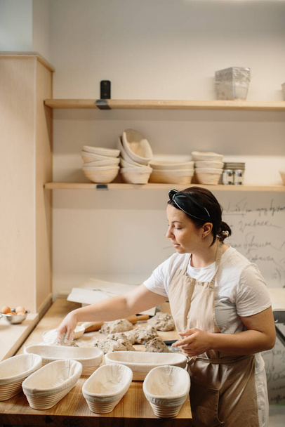 Female baker kneading a dough in bakery sho - Photo, image