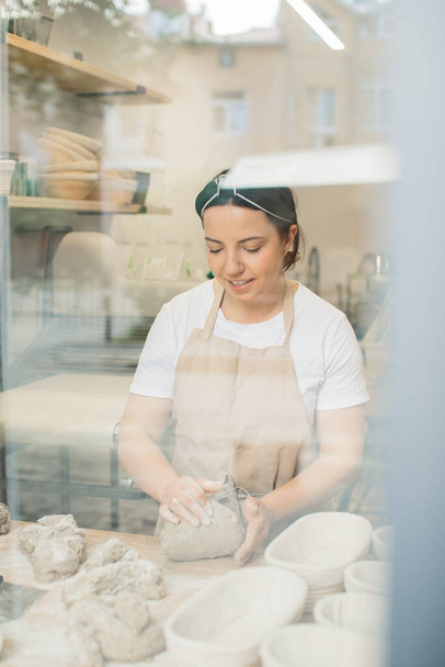 Female baker kneading a dough in bakery sho - Foto, imagen