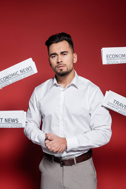 бородатый бизнесмен в белой рубашке рядом с газетами на красный - Фото, изображение