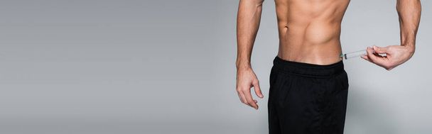 обрізаний вид без сорочки і м'язистий спортсмен впорскує себе в спину на сірому, банер
 - Фото, зображення