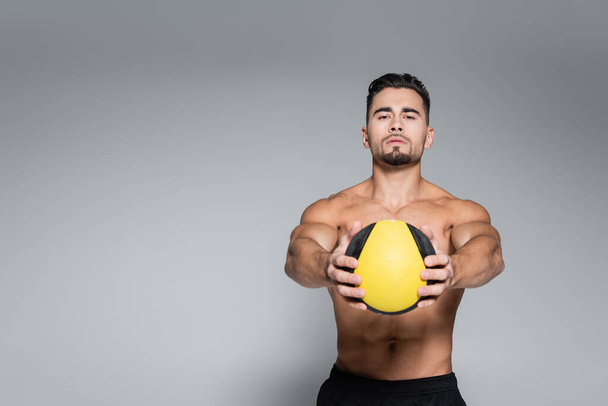 shirtless and bearded sportsman holding ball on grey - Foto, Bild