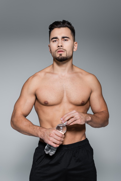 shirtless sportsman holding bottle with water isolated on grey - Foto, Imagem