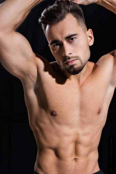 shirtless and muscular sportsman looking at camera isolated on black  - Foto, immagini