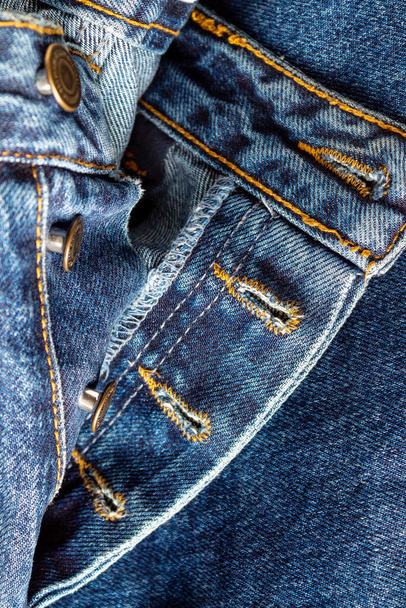 Внутри джинсовых брюк, зашитых оранжевыми нитками, избирательный фокус, крупным планом - Фото, изображение