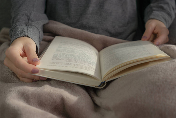 Αγνώριστη καθιστή γυναίκα κρατώντας ένα βιβλίο στα χέρια της - Φωτογραφία, εικόνα