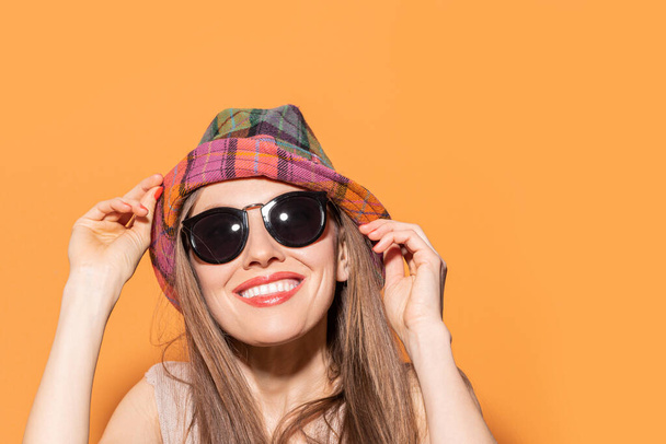 Young caucasian woman with hat and stylish sunglasses isolated on color background - Фото, изображение
