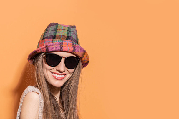 Young caucasian woman with hat and stylish sunglasses isolated on color background - Foto, imagen