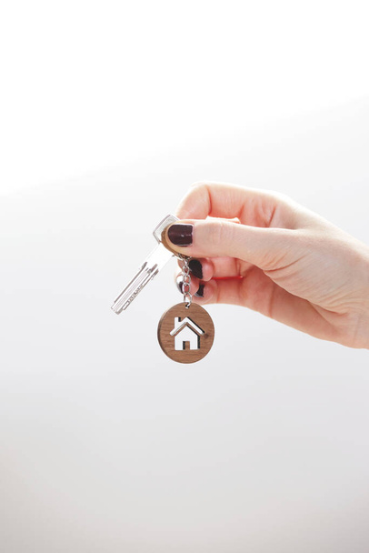 Real estate concept. Keys with a house shaped keychain in a womans hand. - Photo, Image